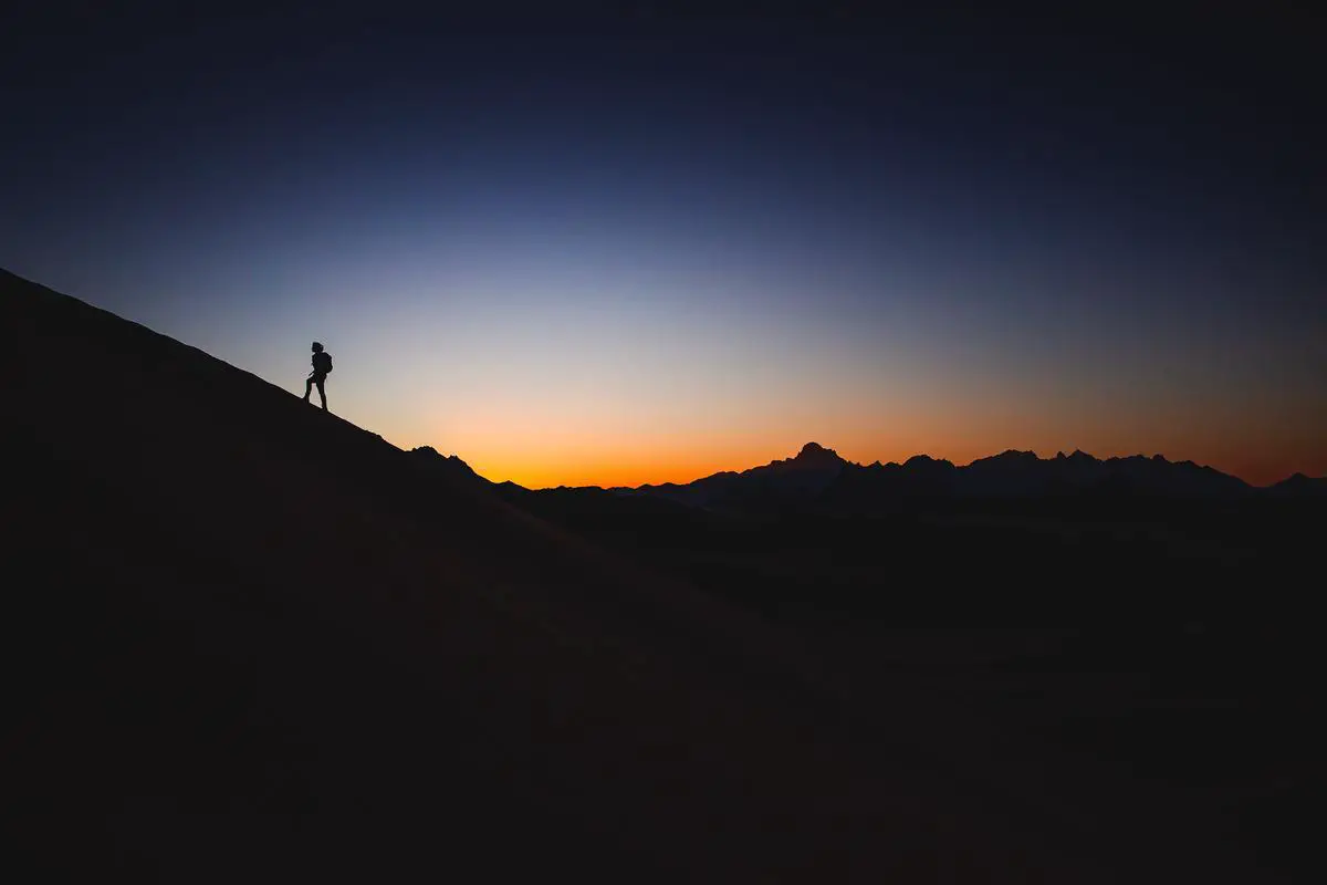 An image showing a person standing on top of a mountain, symbolizing the concept of dreaming bigger and reaching for the impossible.